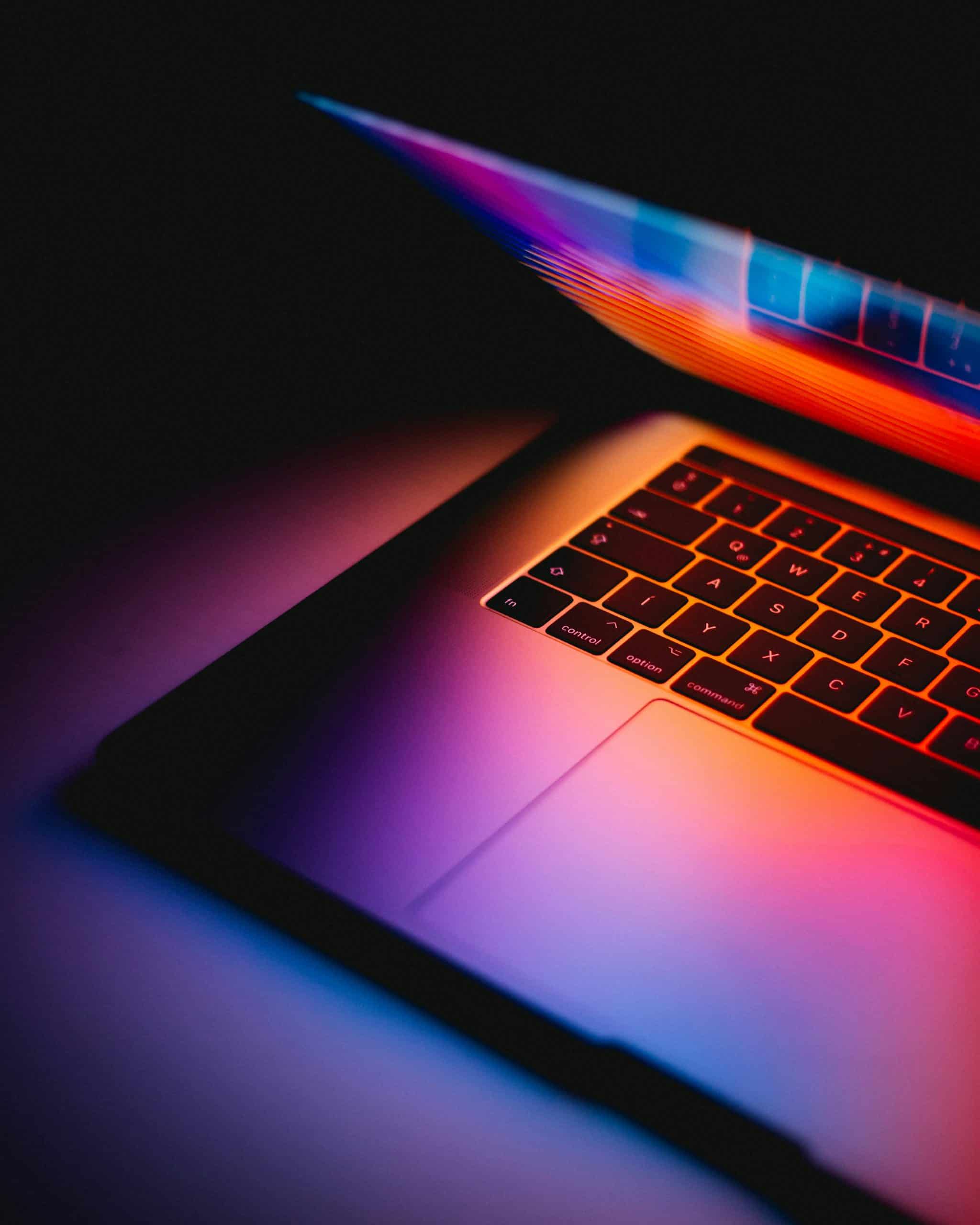 Open laptop computer bathed in purple and orange light